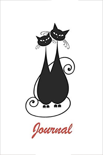 White softcover notebook with two black cats on the cover. Red text says journal.