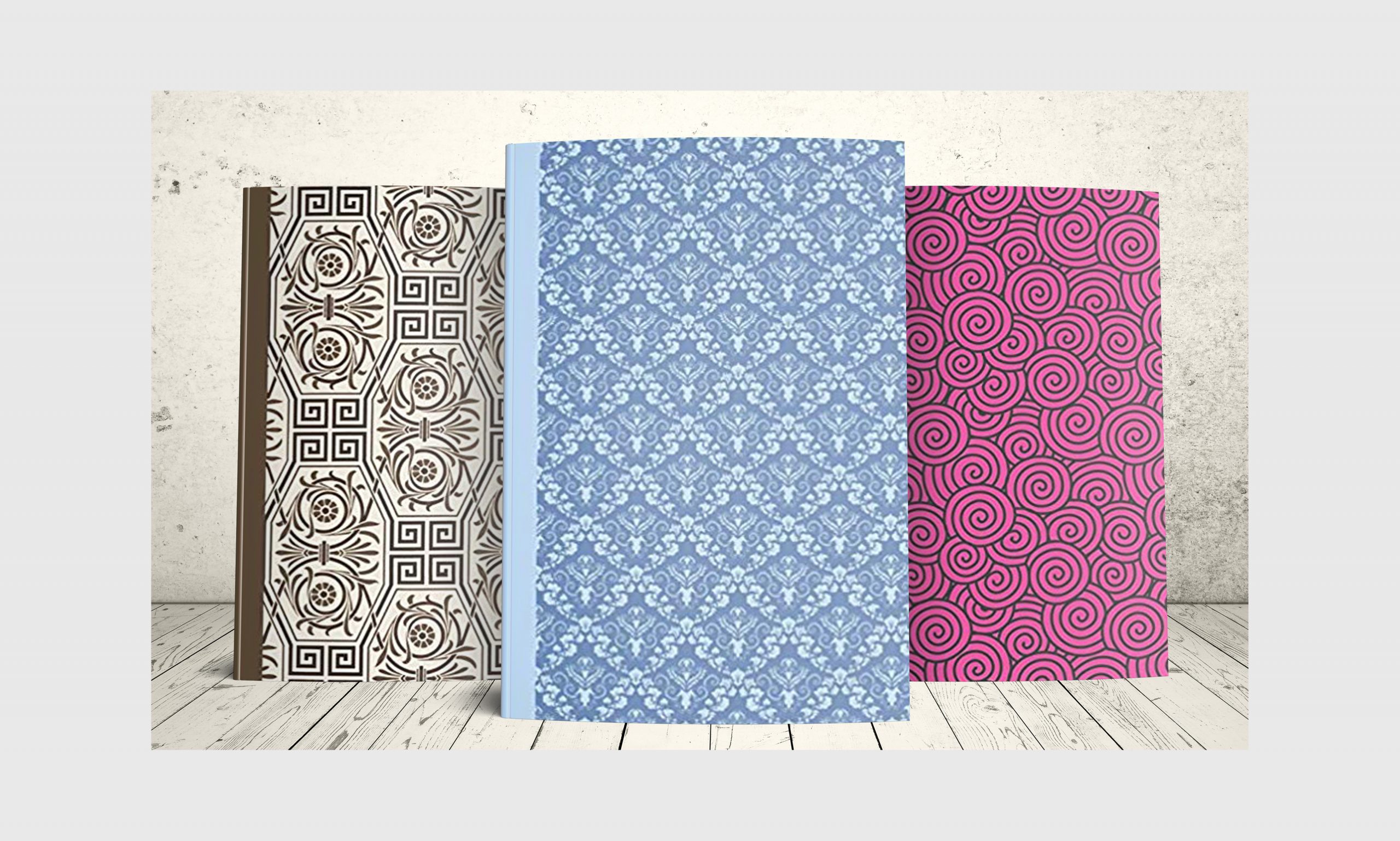 Three journals with patterns on the cover, blue, pink and brown.