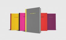 Five journal notebooks with the phrase TELL ME ABOUT IT on the cover in a variety of color combinations: Grey and yellow, pink and black, red and black, purple and green, yellow and red.